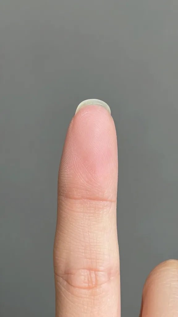 Single fingertip gently touching dried smudged nail.
